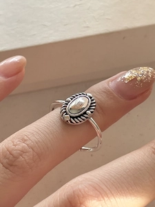 On-finger view of a vintage oval sterling silver ring with a braided textured border