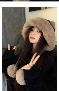 Dettaglio cappello invernale marrone in peluche con paraorecchie e grandi pompon decorativi