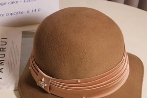 Close-up of wool fedora with champagne satin ribbon, white pearls and rhinestone star