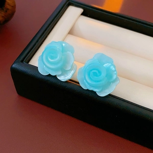Gros plan de boucles d'oreilles roses en résine bleue dans un écrin à bijoux noir