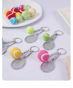 Detailed close-up of mini tennis racket and colorful ball keychains on white background