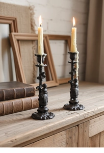Détail de bougeoirs vintage en fonte avec figurines décoratives sur une table en bois
