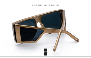 Side angle display of thick geometric gold frame sunglasses with dark grey lenses