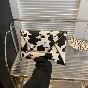 Macro shot of stylish cow print envelope clutch with luxury gold metallic trim decoration