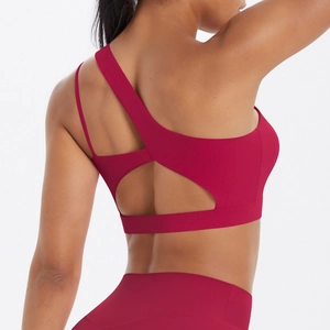 Detail of red sports bra featuring asymmetric strap and cross-back cutout design