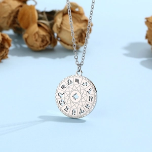 Detailed macro view of a silver celestial zodiac compass pendant with hollow-out engravings
