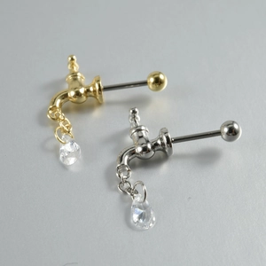 Detail of faucet-shaped piercing jewelry with hanging water drop zircon in gold and silver