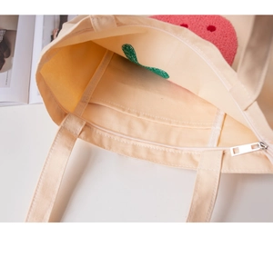 Detail view of canvas tote bag featuring interior zipper pocket and soft floral embroidery