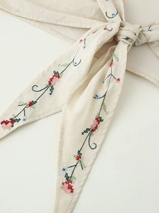 Gros plan sur la broderie florale et la texture lin-coton d'un haut dos nu ivoire