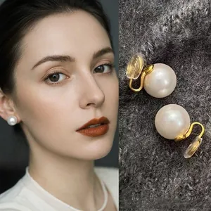 Elegant acrylic pearl stud earrings with gold plating on a female model and textured background