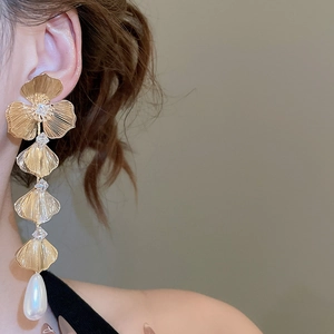 Detail of 18K gold plated flower earrings with drop pearl on a model's ear