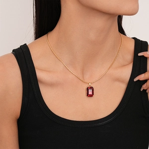 Detail of red rectangular gemstone necklace with gold chain worn on the neck