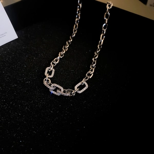Silver chain necklace with zircon-inlaid geometric links on a textured black background