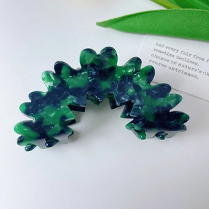 Detailed view of wavy cloud hair claw with green and blue tortoiseshell pattern finish