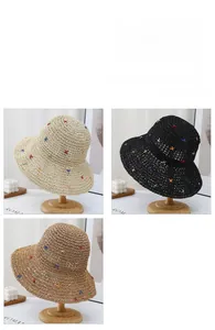 Detail of wide brim straw hats in three colors with delicate cross-stitch embroidery