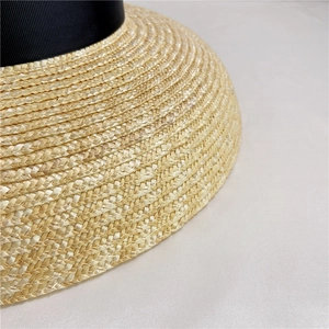 Close-up of high-density spiral weave texture on a straw hat with black satin ribbon