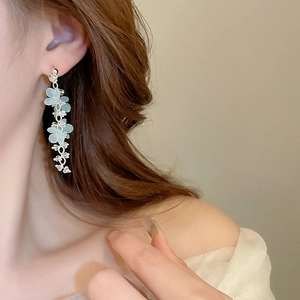 Detail shot of light blue floral tassel earrings worn to show the long elegant drape