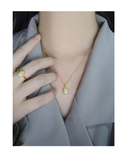 Close-up of a delicate gold S925 silver necklace with an oval opal sunburst pendant
