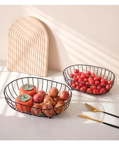 Close-up of black metal wire fruit basket with oval hollow design in natural sunlight