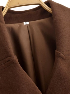 Detail view of the brown wool jacket collar and inner lining on a wooden hanger