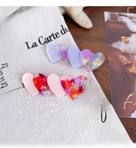 Close-up of heart-shaped acetate hair clips with marble texture and glitter details
