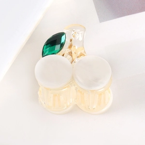 Detail of cherry-shaped hair claw with cream acrylic beads and green rhinestone leaves