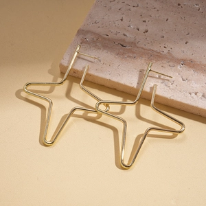 Macro view of gold minimalist hollow five-pointed star stud earrings on stone