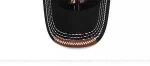 Macro detail of black baseball cap brim with white stitching and brown leather trim