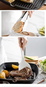 Macro shot of white silicone tongs and spatula with natural wooden handles in a kitchen