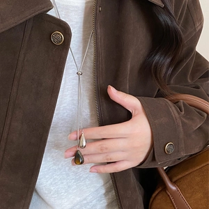Close-up of silver Y-shaped necklace with polished and tiger-eye drop pendants