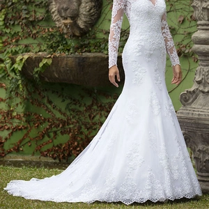 Elegant white mermaid lace wedding dress with a deep V-neck and long sleeves on a model