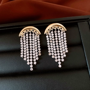Gros plan de boucles d'oreilles dorées avec glands en strass sur un support en velours