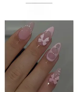 Detail of pink almond press-on nails with sweet bow and delicate pearl embellishments