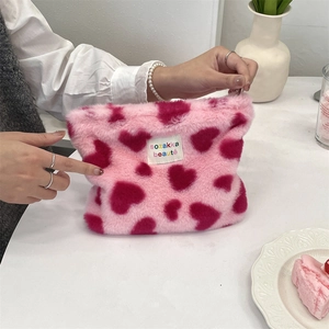 Detail of pink leopard plush makeup bag with heart pattern and woven logo tag