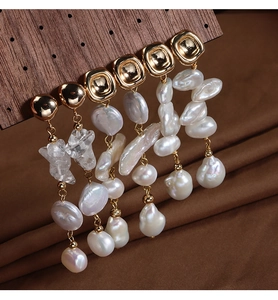 Detailed view of Baroque pearl earrings with crystal drop on a wooden display stand