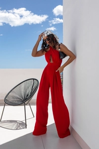 Detail of red halter jumpsuit showing side waist cut-out and wide-leg woven fabric flow