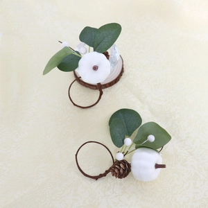Detail of white pumpkin napkin rings with eucalyptus leaves and pine cones for fall decor