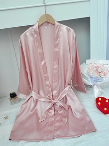 Detailed close-up of pink satin bathrobe fabric with a waist tie and size S label