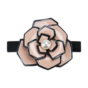 Macro detail of French acetate camellia hair clip with glossy petals and central pearl