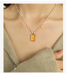 Primo piano della collana di perle con ciondolo a tulipano dorato indossata da una modella