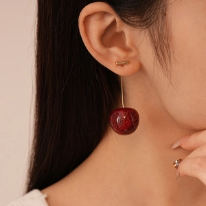 Close-up of red resin cherry earrings with glitter finish worn by a model