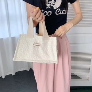 Close-up of cream canvas tote bag featuring 3D lace flower details and woven brand label