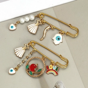 Detail of gold safety pin brooches with evil eye pendants and shell charms