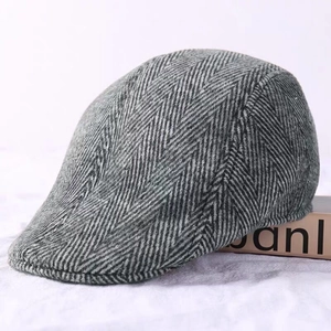 Close-up of grey herringbone wool flat cap showing textured fabric and side profile
