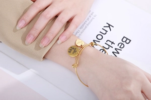 Detail of gold heart and circle charms engraved with Love and Mi Mama on bangle