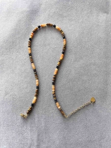 Detail of colorful tiger eye beads and orange agate necklace with gold heart charm