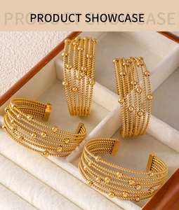 Macro shot of layered gold titanium bangles with twisted texture and bead details