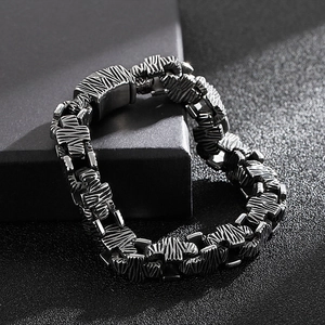 Detail of gun-black stainless steel bracelet with textured links and a secure folding clasp