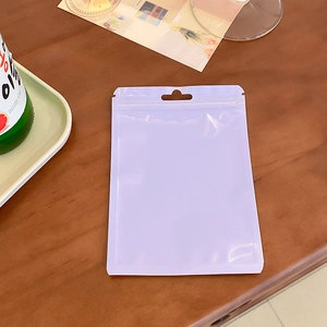 Top view of a thick lavender resealable holographic pouch on a minimalist wooden table