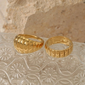 Polished gold minimalist croissant and ribbed stainless steel rings on a stone surface